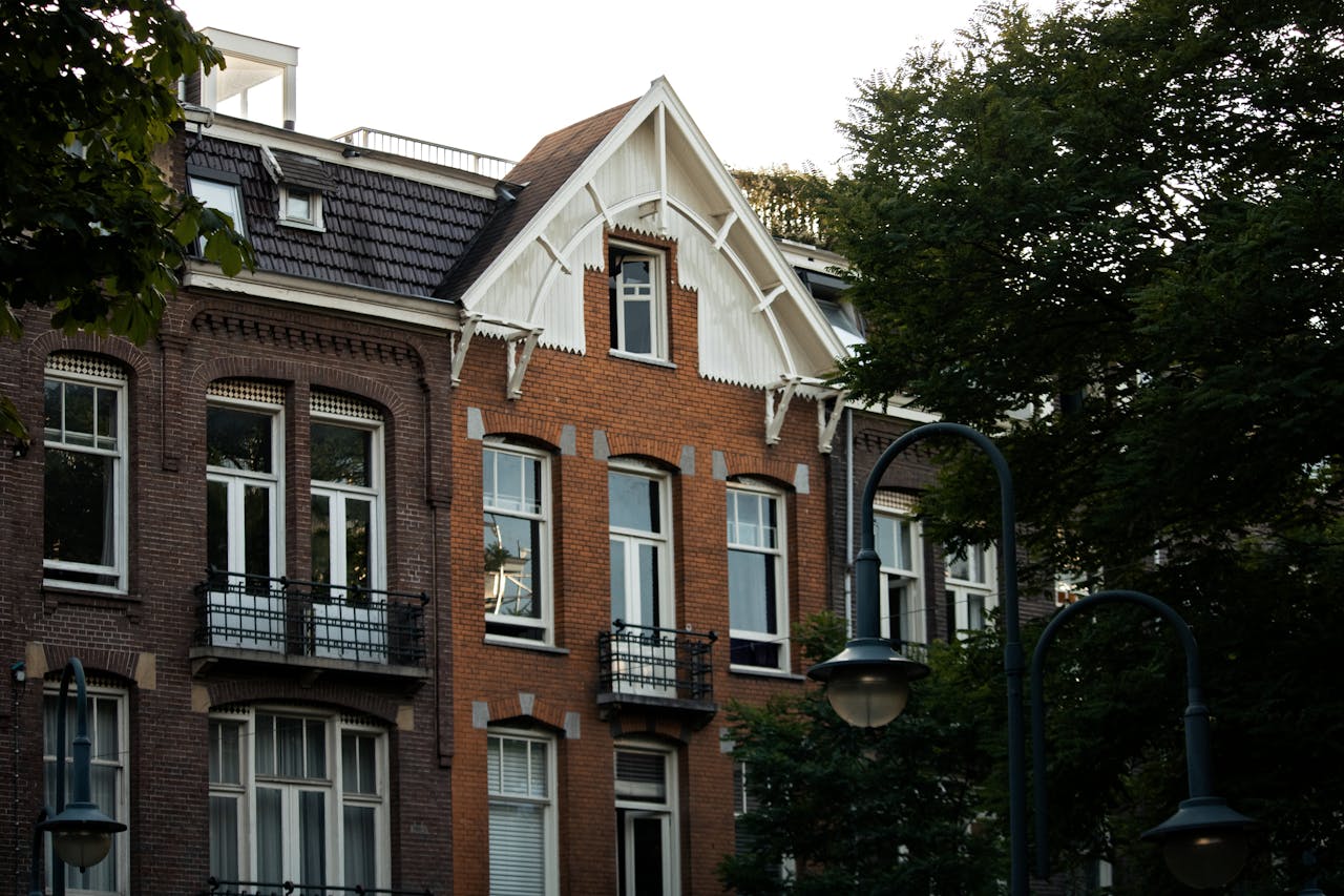 services-03 Vintage-style brick building in Amsterdam surrounded by trees, showcasing classic architecture.