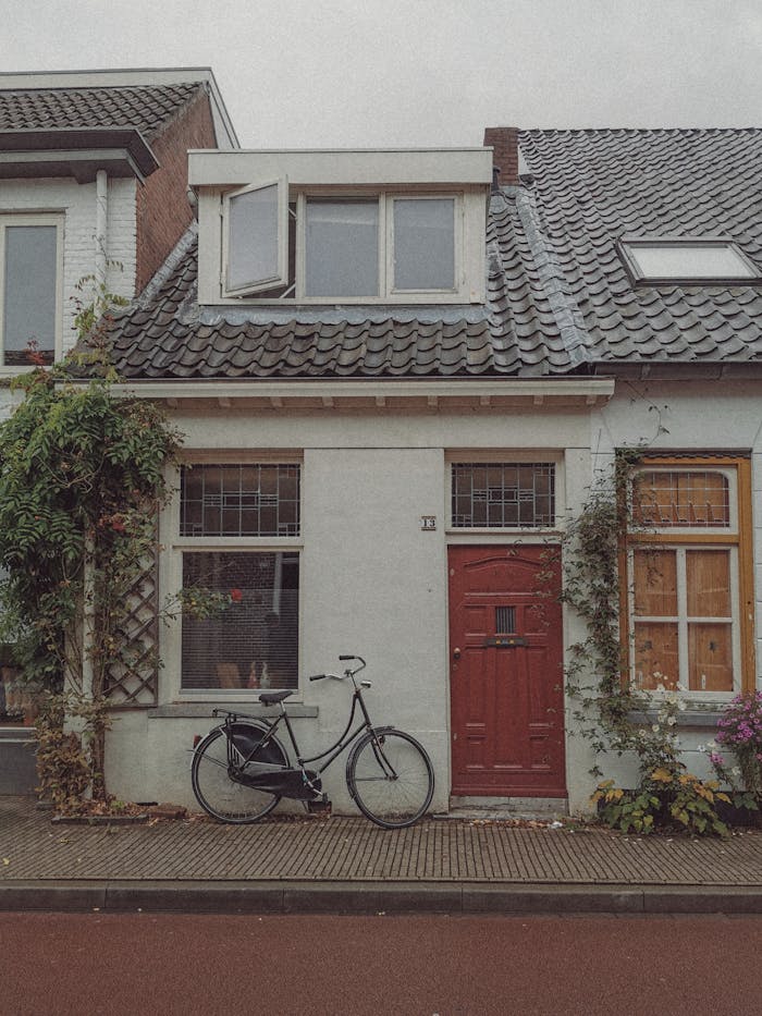 pexels photo 20697905 Cozy urban house with a vintage bicycle in front of a vibrant red door.