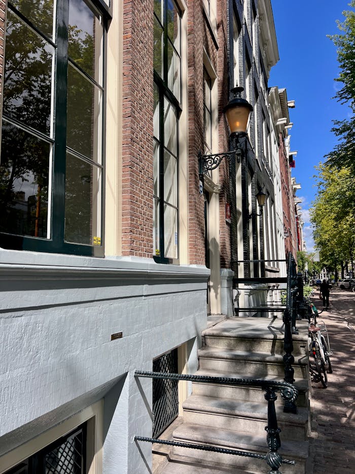 gallery-1 Elegant Amsterdam houses lined along a picturesque canal street on a sunny day.