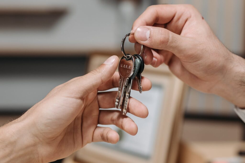 pexels photo 8112169 A close-up image of two hands exchanging a set of keys indoors.